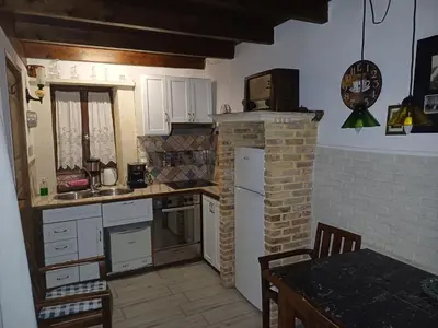 a kitchen with white cabinets and a brick fireplace at Villa Margot in Chania Town