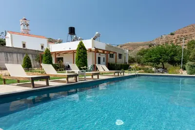 a swimming pool with chairs and a house at Agarathos Tradiitonal Apartments & Rooms with Pool Kaliviani -On the road to Balos in Kissamos