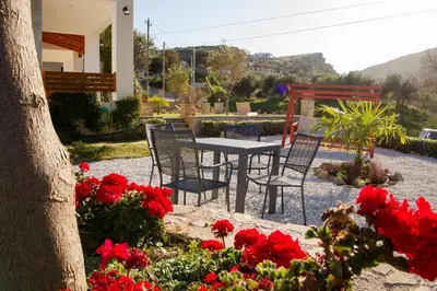 a patio with a table and chairs and red flowers at Agarathos Tradiitonal Apartments & Rooms with Pool Kaliviani -On the road to Balos in Kissamos