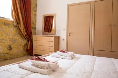 a bedroom with a white bed with towels on it at Agarathos Tradiitonal Apartments & Rooms with Pool Kaliviani -On the road to Balos in Kissamos