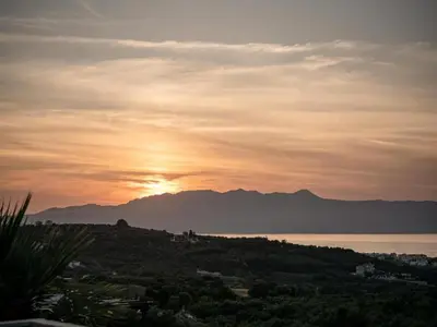 a sunset over the water with mountains in the background at Studio in Ravdoucha with Sea View Balcony in Ravdhoúkha