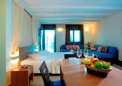 a bedroom with a bed and a table with a bowl of fruit at Minos Village in Agia Marina Nea Kydonias