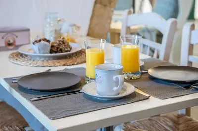 a table with plates and glasses of orange juice at Traditional Sea Side Cottage in Maleme