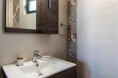 a bathroom with a sink and a mirror at Traditional Sea Side Cottage in Maleme