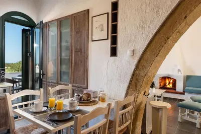 a dining room with a table and a fireplace at Traditional Sea Side Cottage in Maleme