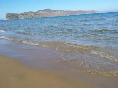 a beach with the ocean and people swimming in the water at Rubini Homes in Agia Marina Nea Kydonias