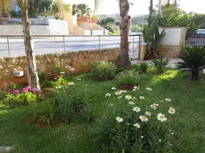 a garden with flowers in the grass next to a fence at Rubini Homes in Agia Marina Nea Kydonias
