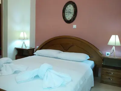 a bedroom with a bed with white pillows and a clock at Rubini Homes in Agia Marina Nea Kydonias