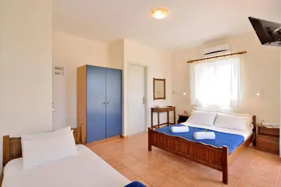 a bedroom with two beds and a blue cabinet at Katerina Rooms Agii Apostoloi in Kato Daratso