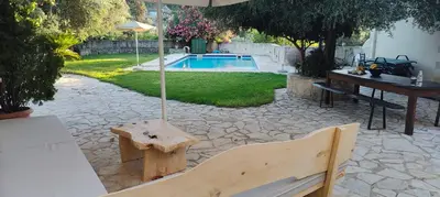 a patio with a bench and an umbrella and a pool at Filippou Villa - Living in Nature in Fílippos