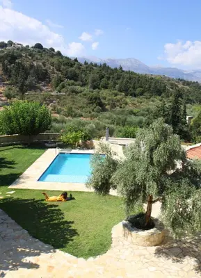 a woman laying on the grass next to a swimming pool at Filippou Villa - Living in Nature in Fílippos