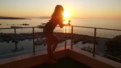 a woman standing on a balcony watching the sunset at Panoramic Sea View in Chania Town