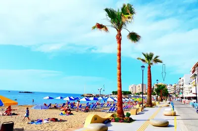 a beach with people laying on the sand and palm trees at Panoramic Sea View in Chania Town