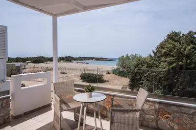 a balcony with a table and chairs and a view of the beach at Cedar Bay Beachside Villas in Palaiochóra