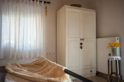 a room with a bed and a white cabinet and a window at Petra & Elia in Megála Khoráfia