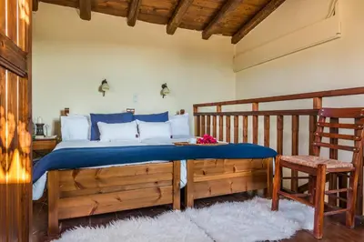 a bedroom with a bed with blue sheets and a chair at Antheia Houses in Vamos