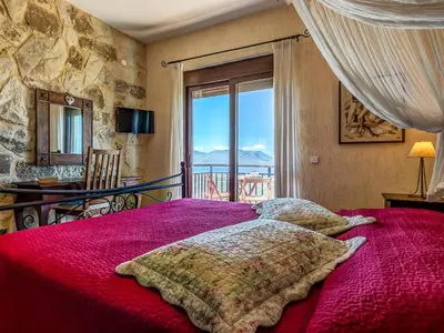 a bedroom with a bed with a red comforter and a window at Villa Kalliani in Kissamos