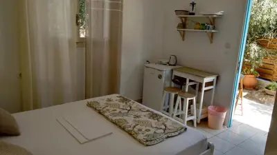 a small room with a bed and a table and a counter at Kampos Rooms in Palaiochóra