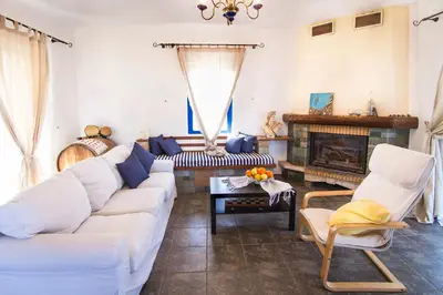 a living room with a white couch and a fireplace at Mantilida Villa & Studio in Kissamos