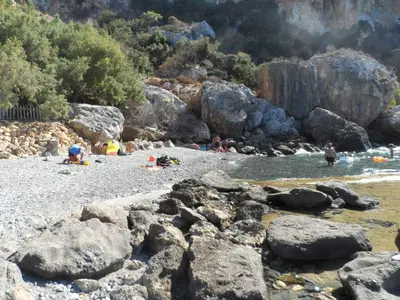 a group of people playing in the water on a rocky beach at Michalis Holiday Home in Ravdhoúkha