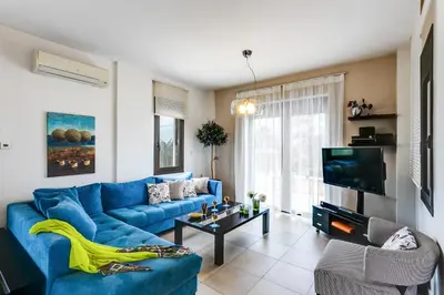 a living room with a blue couch and a tv at Villa Selena in Stalos