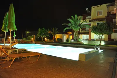 a swimming pool at night with chairs and umbrellas at Eliros Studios in Stalos