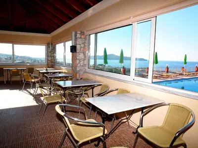 a restaurant with tables and chairs and a large window at Eliros Studios in Stalos