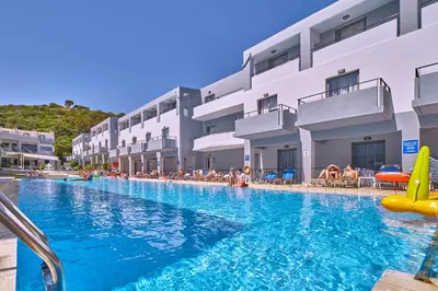 a swimming pool at a resort with people sitting on chairs at Sunrise Village Hotel - All Inclusive in Plataniás