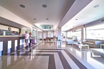 a lobby with two people standing at a bar at Sunrise Village Hotel - All Inclusive in Plataniás
