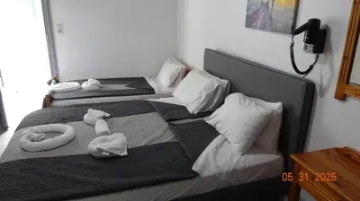 two beds in a room with towels on them at Scirocco Rooms in Loutro