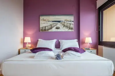 a bedroom with a large white bed with purple walls at Lavender Villas Chania in Agia Marina Nea Kydonias
