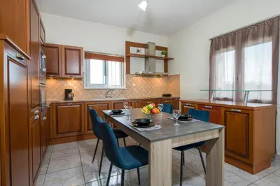 a kitchen with a table with blue chairs and a table sidx sidx sidx at Villa Ifigeneia Private Hot Tub Rooms in Kalathas