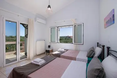 a bedroom with two beds and two windows at Villa Ifigeneia Private Hot Tub Rooms in Kalathas