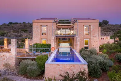 a brick house with a swimming pool in front of it at Kaminia Villa in Makhairoí