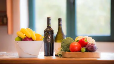 a table with two bottles of wine and a bowl of fruits and vegetables at Villa Mathea in Kounoupidhianá