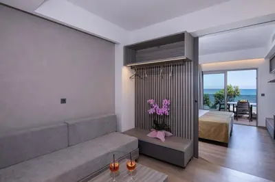 a living room with a couch and a bedroom at Creta Palm Resort Hotel & Apartments in Stalos