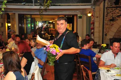 a man holding a vase of flowers in a restaurant at Mithos Apartments in Agia Marina Nea Kydonias