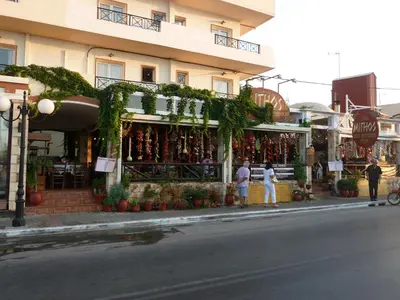 a store on a street with people standing in front of it at Mithos Apartments in Agia Marina Nea Kydonias