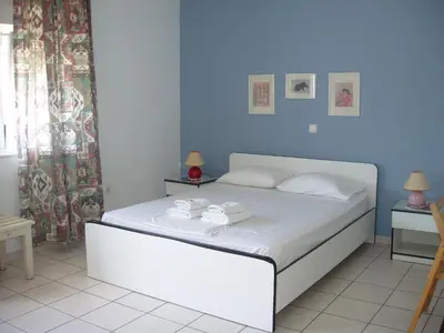 a bedroom with a white bed with blue walls at Aris Apartments in Gerani Chanion