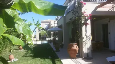 a courtyard with potted plants and an umbrella at Cretamos Seaside Villas in Kissamos