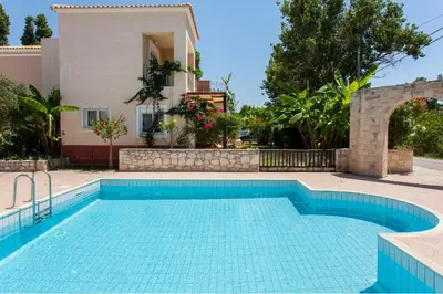 a swimming pool in front of a villa at Cretamos Seaside Villas in Kissamos