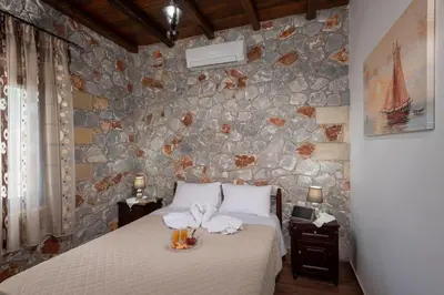 a bedroom with a bed and a stone wall at Sunset Traditional House in Ravdhoúkha