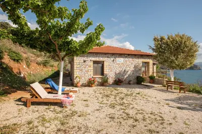 a small stone house with a tree and a chair at Sunset Traditional House in Ravdhoúkha