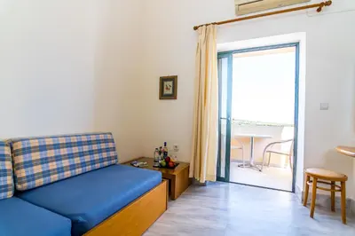 a living room with a blue couch and a sliding glass door at Orestis Hotel Sea View Apartments in Stalos