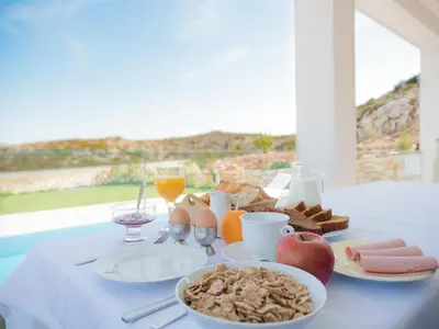 a table topped with plates of food and glasses of orange juice at Κatakis Villas in Agios Onoufrios