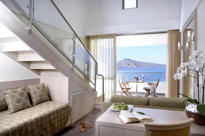 a living room with a couch and a stair case at Thalassa Beach Resort & Spa (Adults Only) in Agia Marina Nea Kydonias
