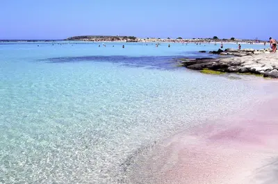 a beach with a bunch of people in the water at Mesogios Beach in Kissamos