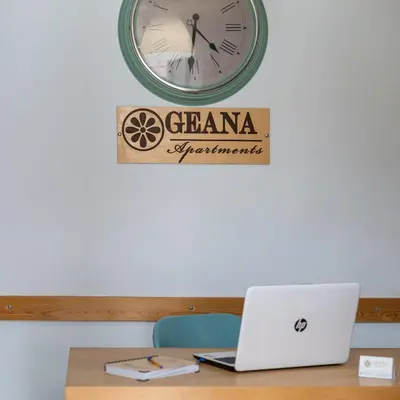 a desk with a laptop and a clock on a wall at Geana Apartments in Chania Town