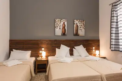two beds in a room with two lamps and paintings on the wall at Geana Apartments in Chania Town