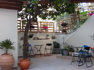 a patio with chairs and a table and potted plants at Geana Apartments in Chania Town